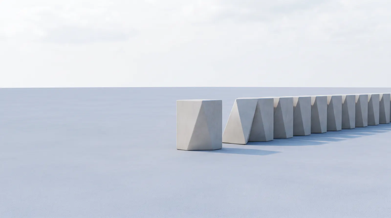 A row of pale blocks receding across a flat surface, the nearest one rounded and the rest sharply angled
